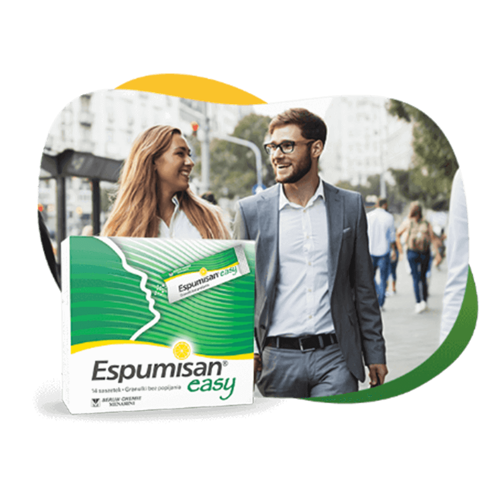 Dwie młode kobiety i mężczyzna w strojach biznesowych idą ulicą, przed nimi paczka Espumisan® EASY.