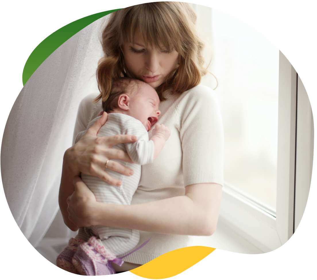 Młoda matka przytula niemowlę do piersi, aby uspokoić je od płaczu spowodowanego kolką niemowlęcą