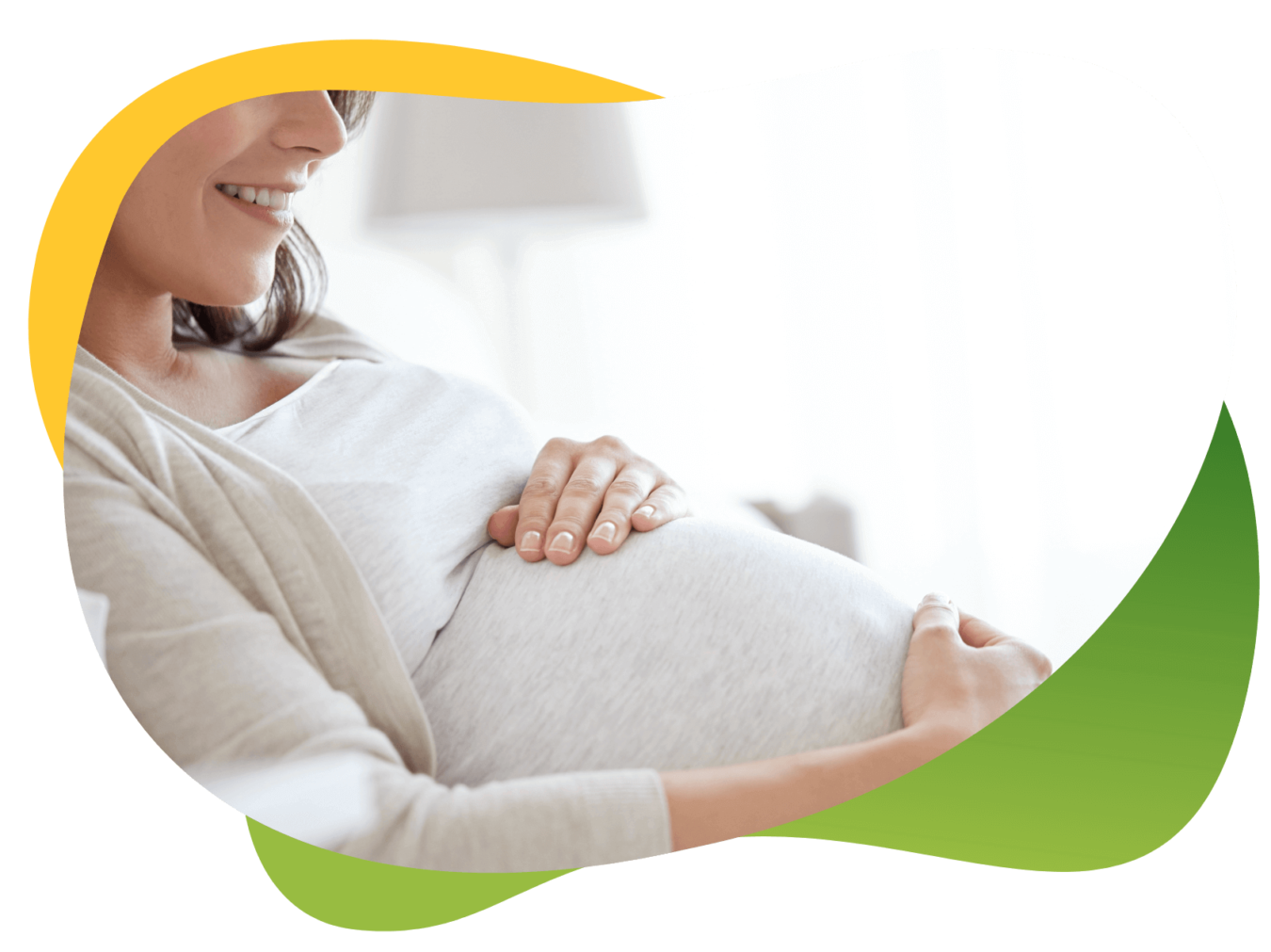 Siedząca kobieta w ciąży, trzyma dłonie na swoim brzuchu, uśmiecha się, ponieważ nie odczuwa wzdęć.
