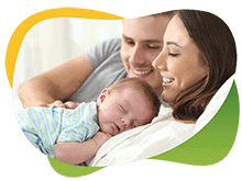 Śpiące niemowlę leży na swojej uśmiechającej się mamie, obok radosny ojciec
